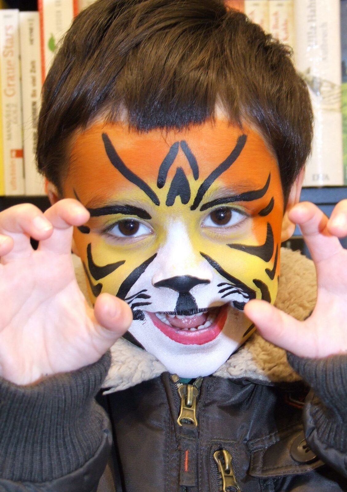Kind mit Tiger-Schminke schaut durch seine Hände